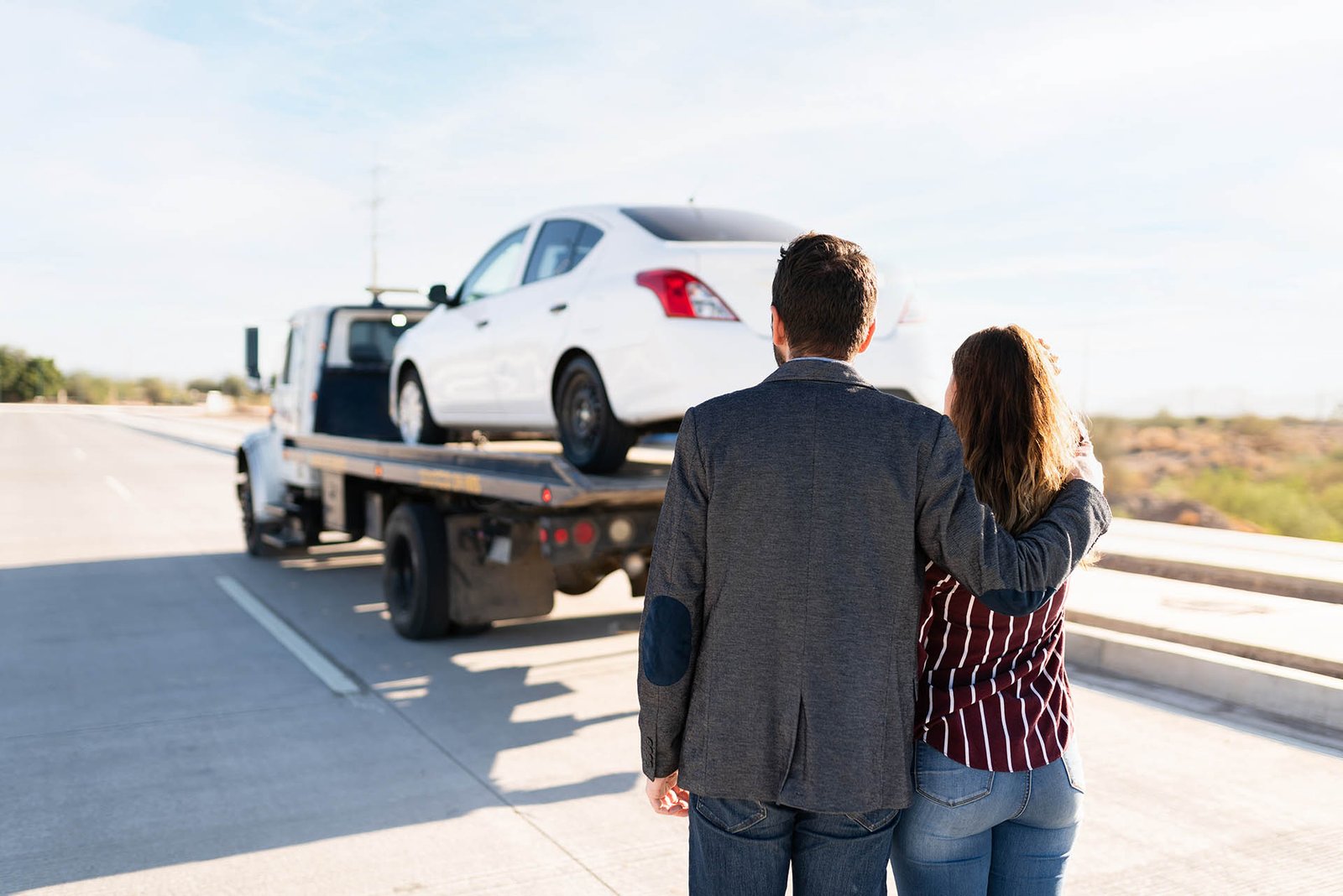 Man and young women hugging as they see their car being towed Flatbed towing service for cars and SUVs across Edmonton and nearby areas